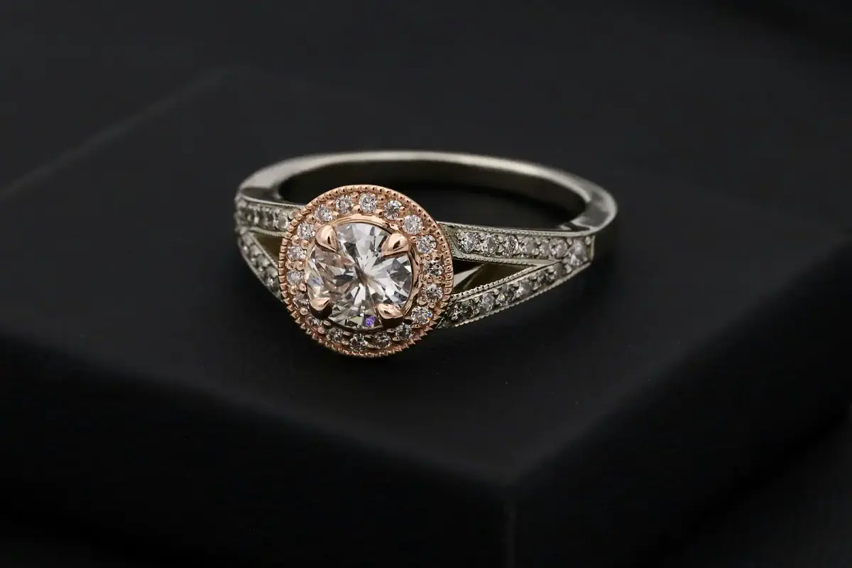 A close-up view of a sparkling, brilliant-cut diamond resting on an elegant gold jewelry setting, showcasing fine craftsmanship